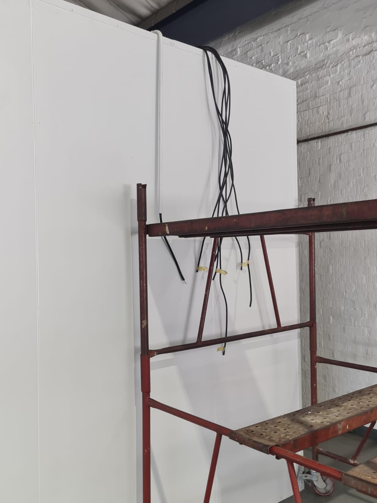 Cold room panels with new wiring being installed above scaffolding