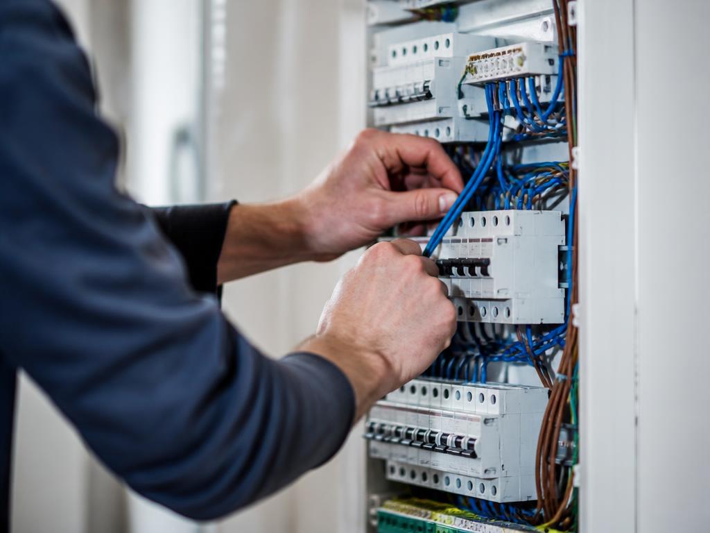 Electrician working inside an open distribution board