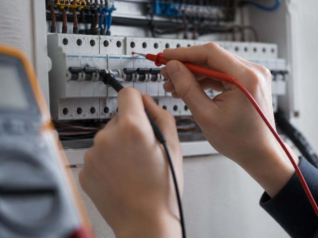 Electrician testing a socket and completing a compliance certificate